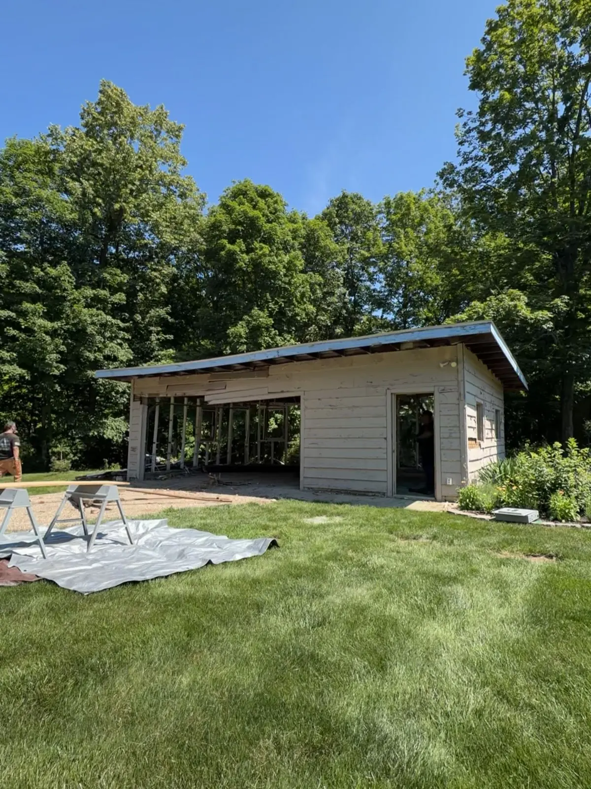 Detached garage with open bays standing at the treeline in Peoria County IL before demolition