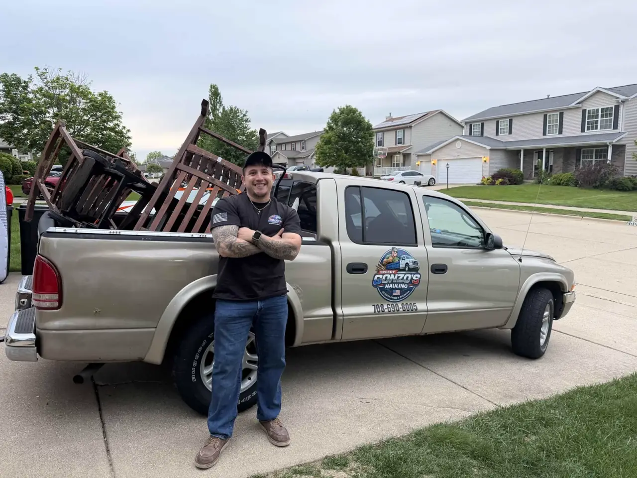 Efren standing in front of the Speedy Gonzo's Hauling truck loaded with cleared furniture