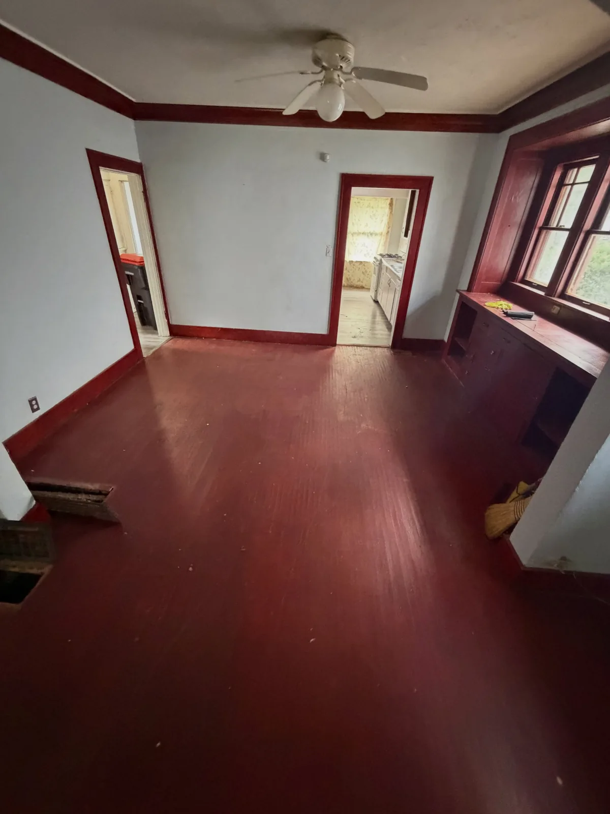 Same Peoria IL living room emptied and swept, bare red hardwood floor showing after cleanout
